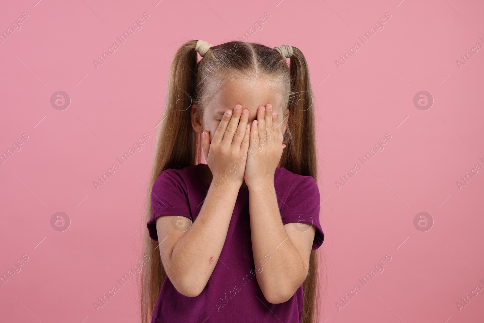 Photo of Resentful girl covering her face with hands on pink background