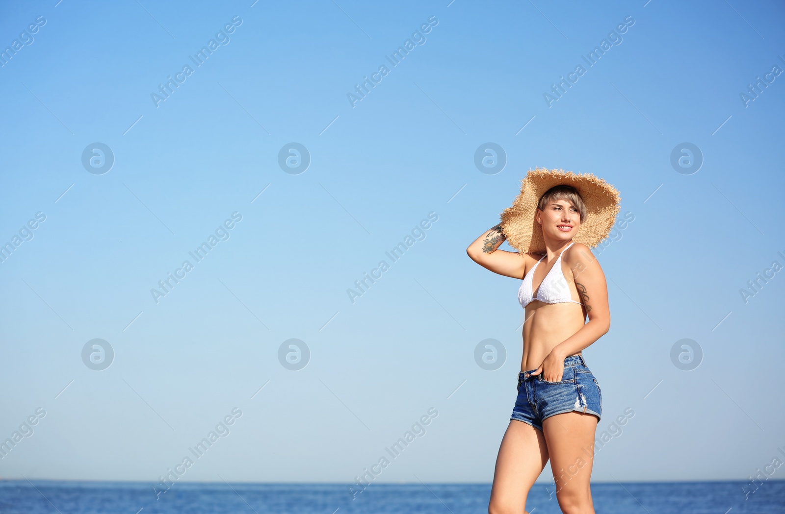 Photo of Young woman in straw hat on beach. Space for text