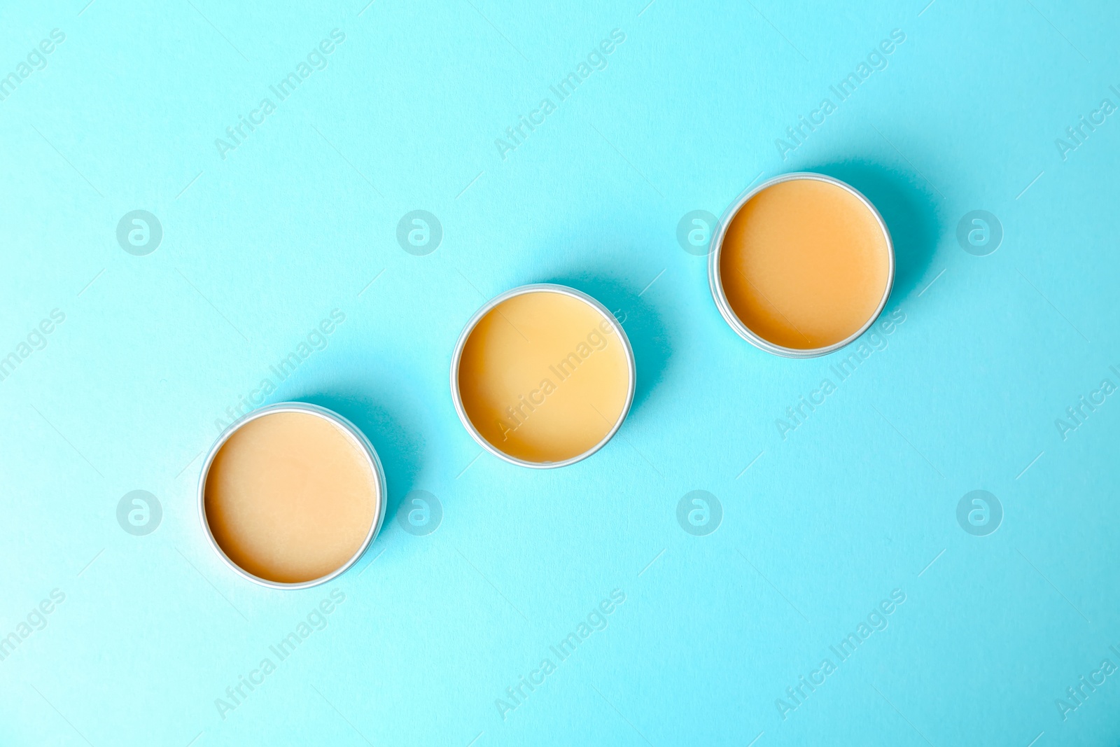 Photo of Flat lay composition with lip balms on color background