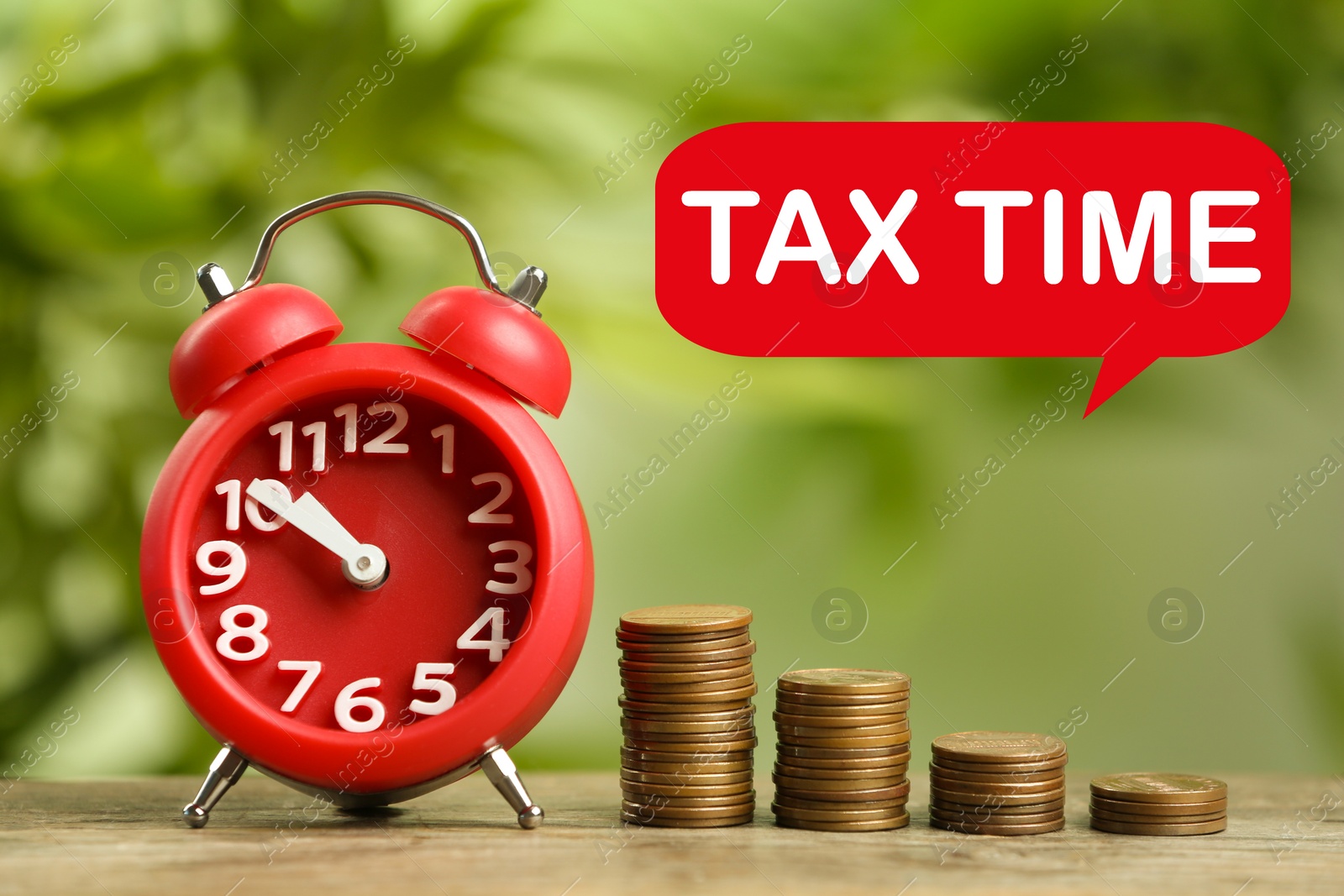 Image of Time to pay taxes. Alarm clock and stacked coins on wooden table