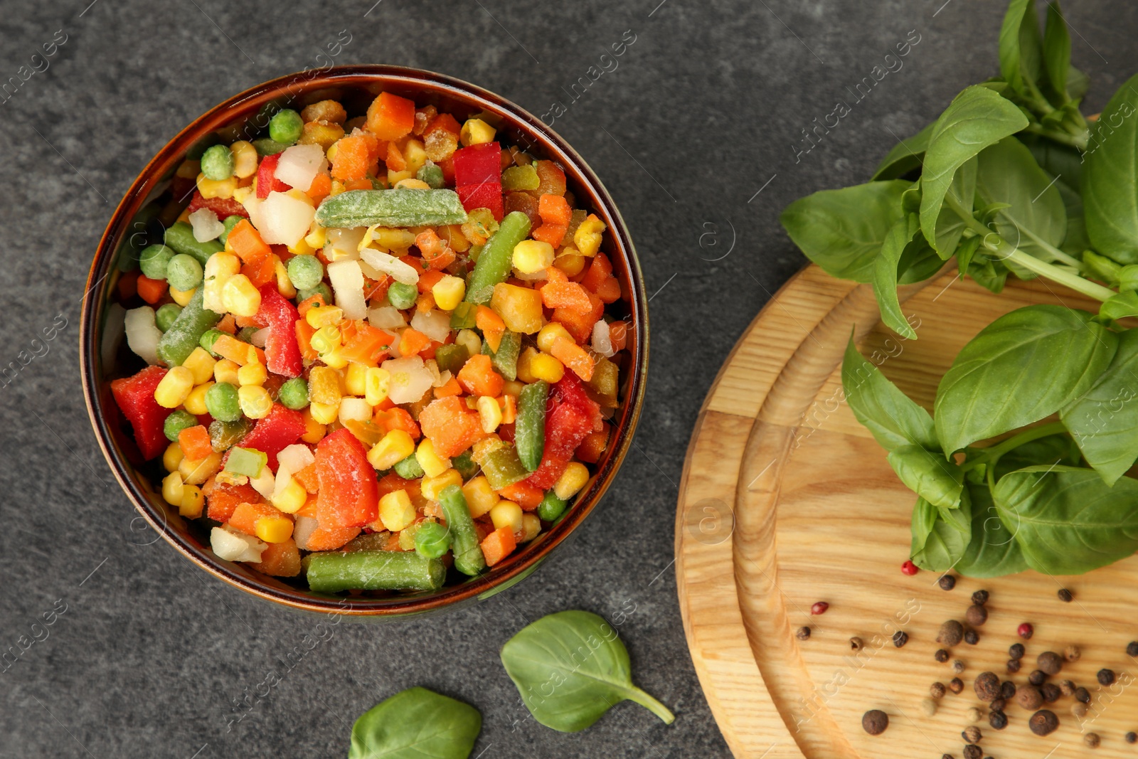 Photo of Different frozen vegetables, spices and fresh basil on grey table, flat lay