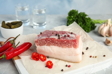 Photo of Composition with pork fatback and spices on white table against blue background