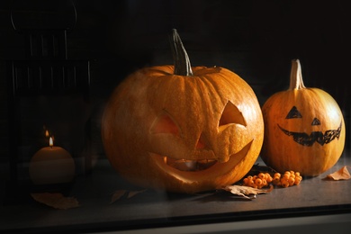 Halloween pumpkin heads. Jack lanterns on windowsill, view through glass