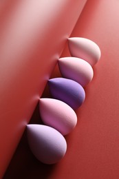 Photo of Many colorful makeup sponges on red background