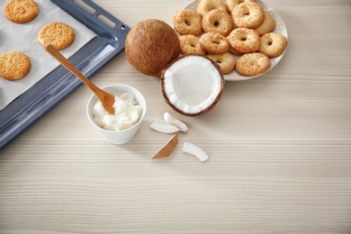 Photo of Bowl with coconut oil and cookies on wooden background