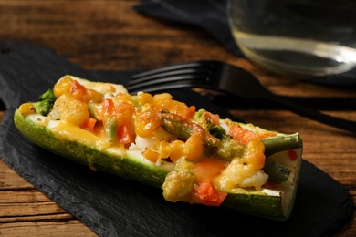 Photo of Baked stuffed zucchini served on wooden table, closeup