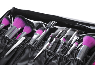 Photo of Stylish case with tweezers and brushes for applying makeup products on white background, closeup