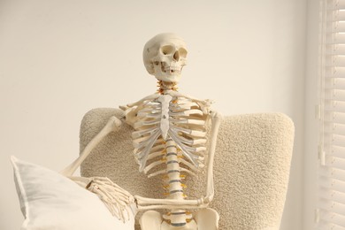 Photo of Waiting concept. Human skeleton sitting in armchair indoors