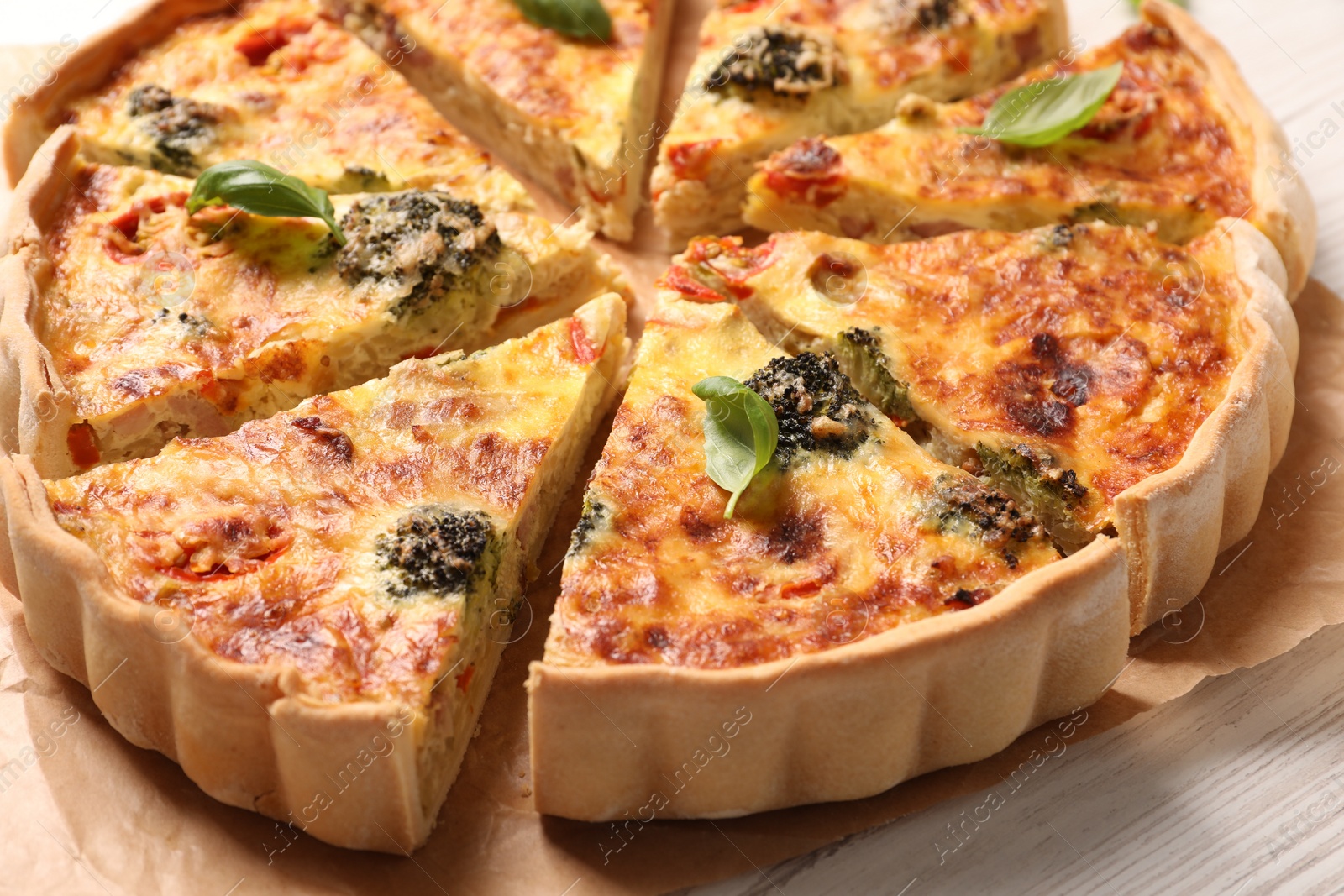 Photo of Delicious homemade vegetable quiche on white wooden table, closeup