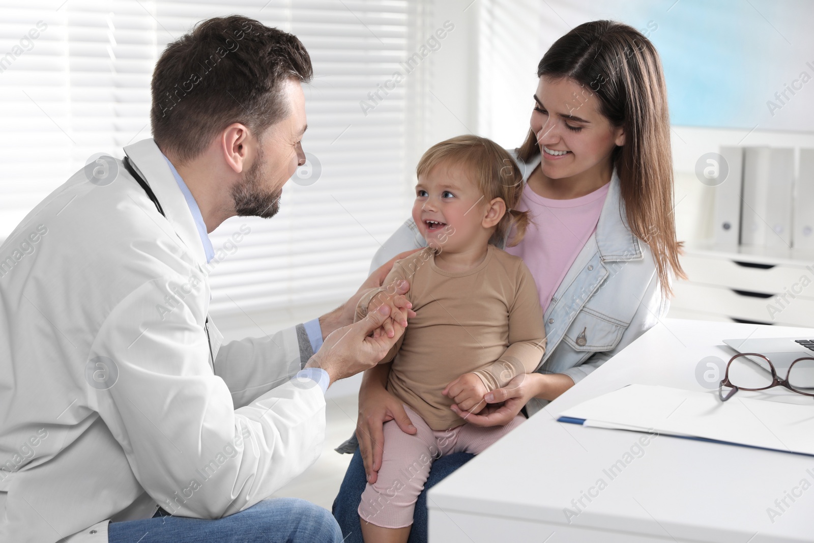 Photo of Mother and her cute baby having appointment with pediatrician in clinic. Doctor examining little girl