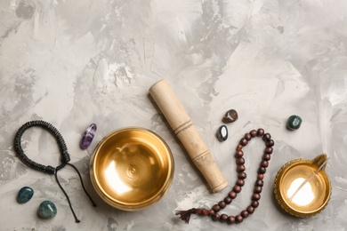 Flat lay composition with golden singing bowl on grey table, space for text. Sound healing