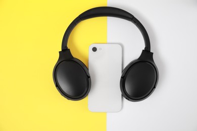 Photo of Modern wireless headphones and smartphone on color background, top view