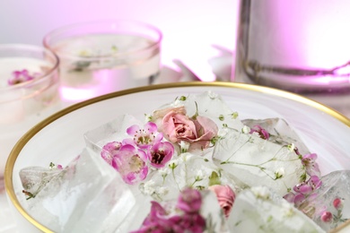 Photo of Bowl of floral ice cubes on table, closeup