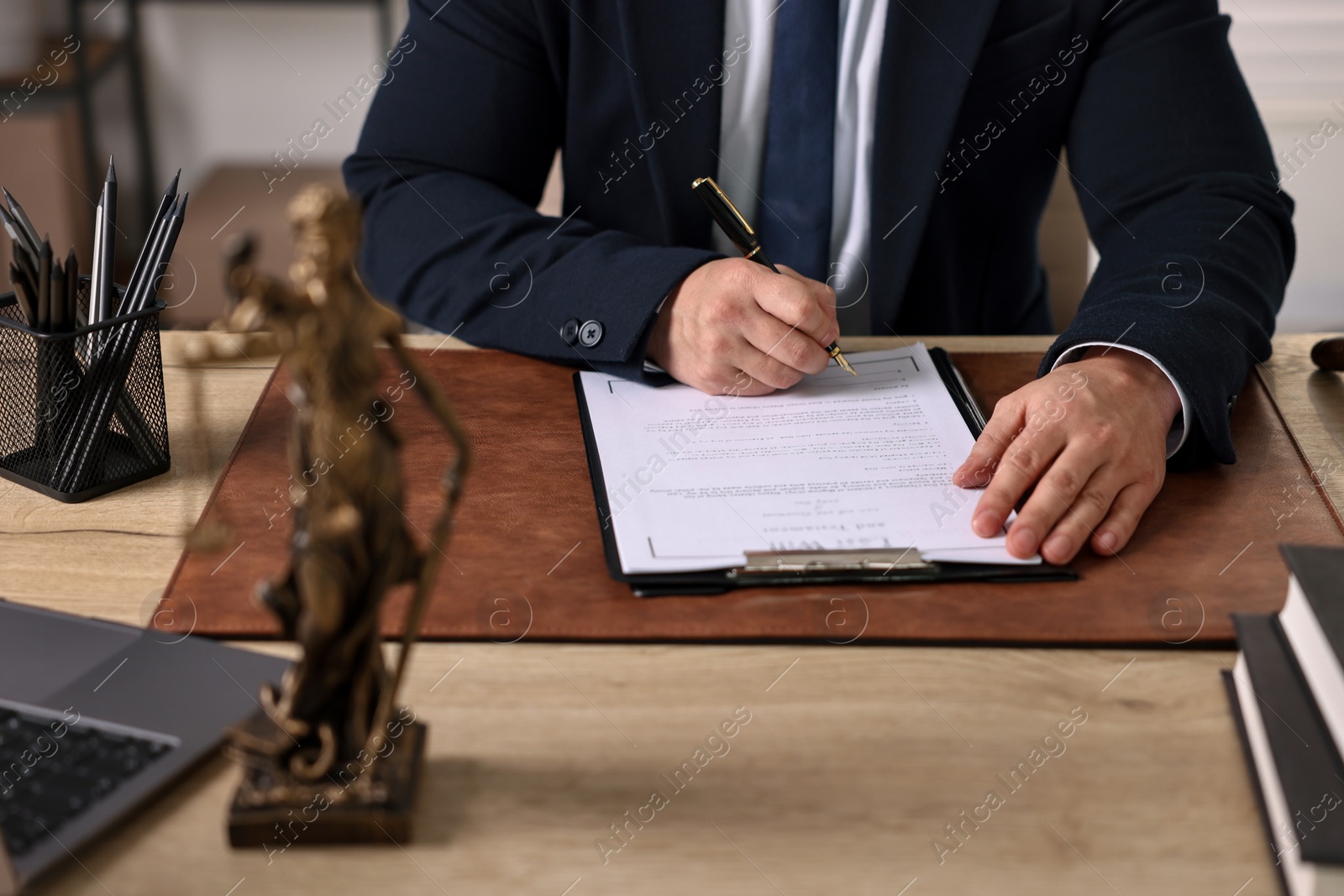 Photo of Notary writing notes at wooden table in office, closeup