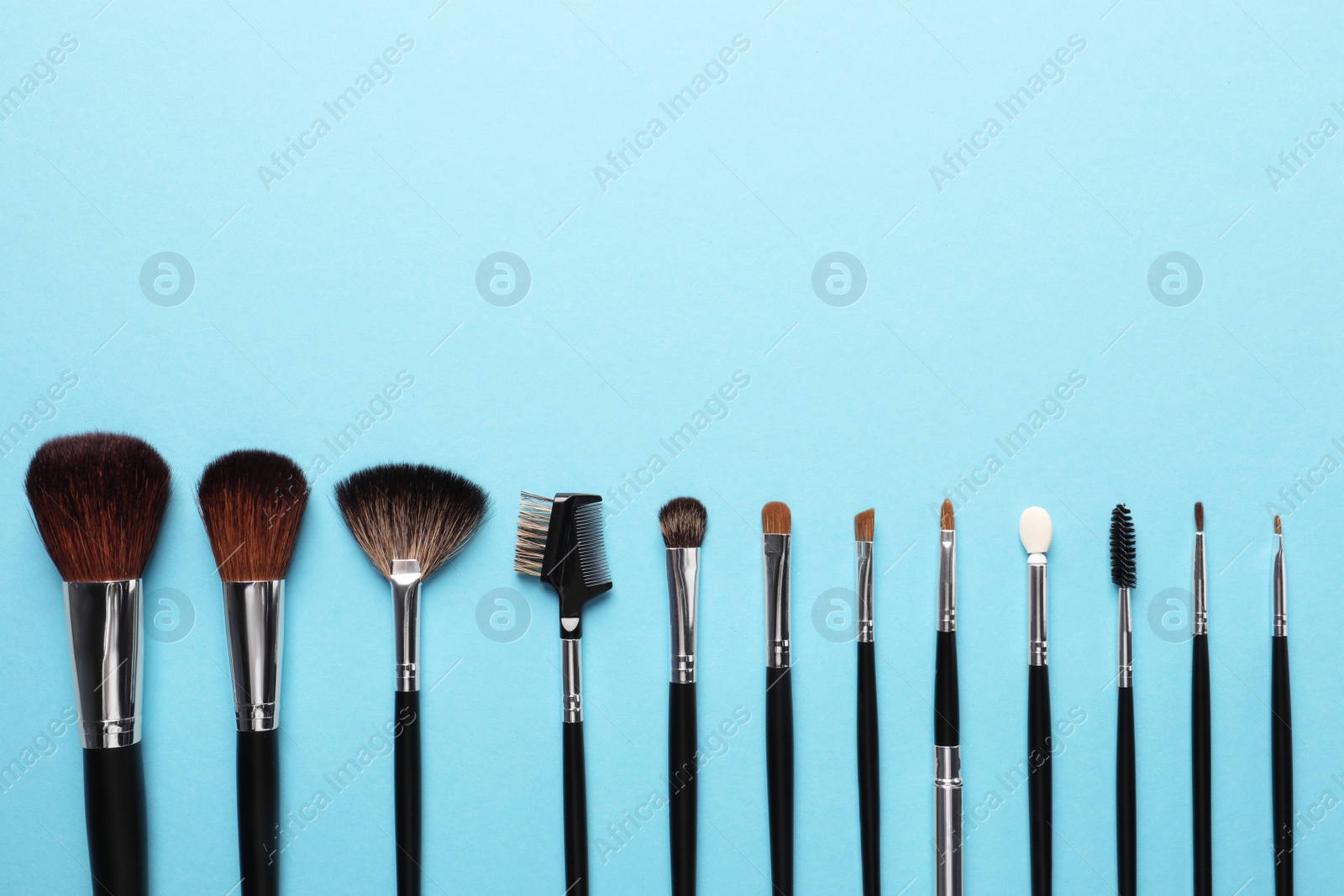 Photo of Set of makeup brushes on light blue background, flat lay. Space for text