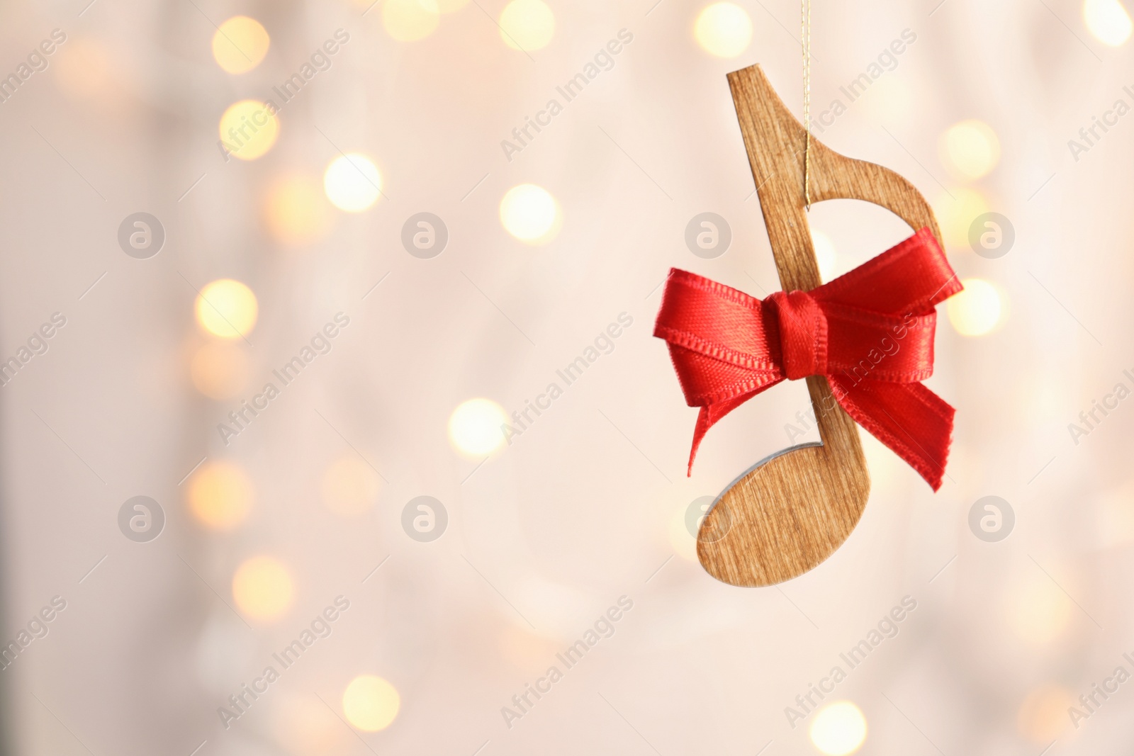 Photo of Wooden note with bow against blurred lights. Christmas music concept