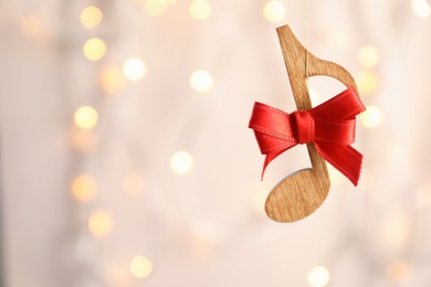 Wooden note with bow against blurred lights. Christmas music concept