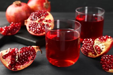 Photo of Tasty pomegranate juice in glasses and fresh fruits on black wooden table, closeup