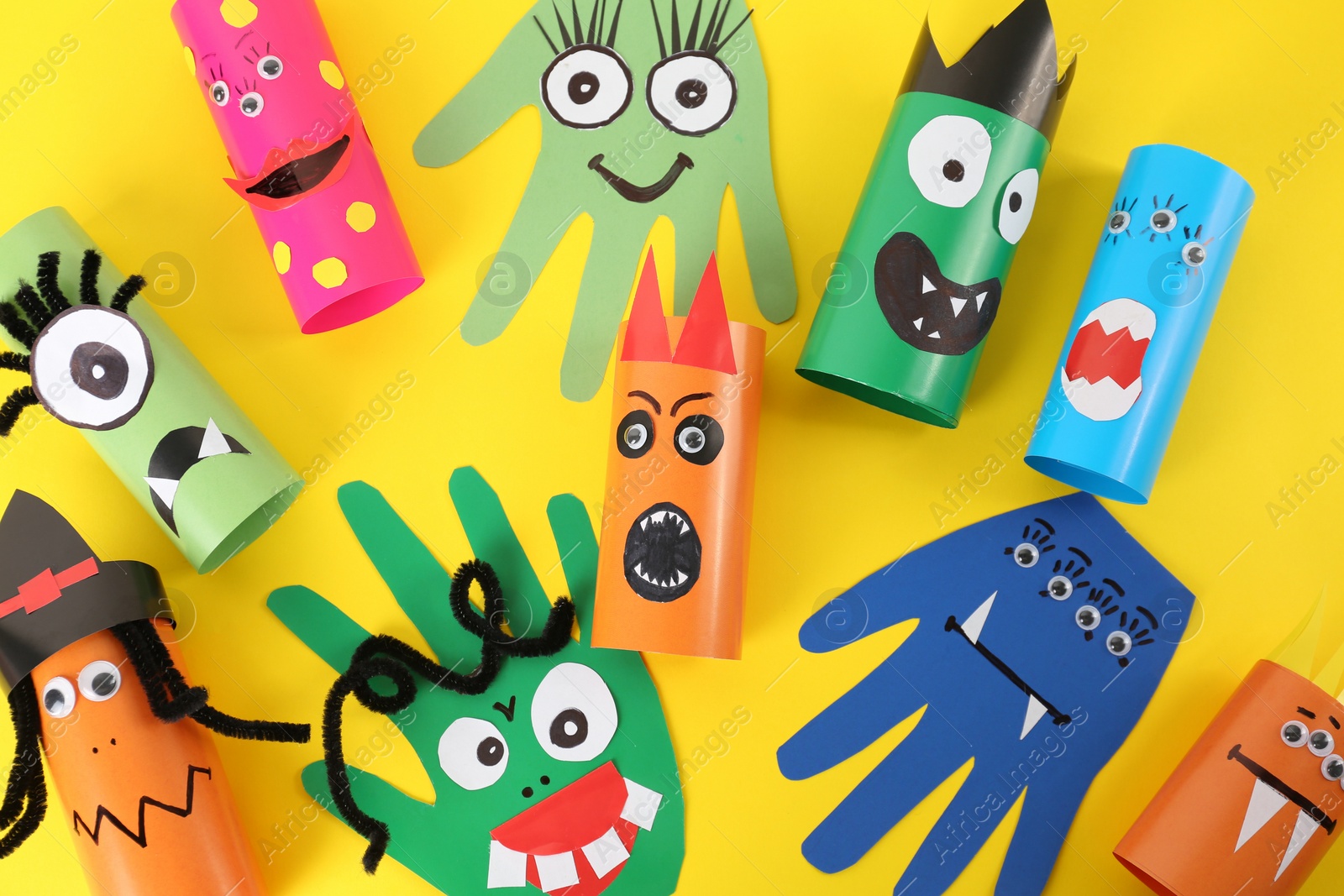 Photo of Funny monsters on yellow background, flat lay. Halloween decoration