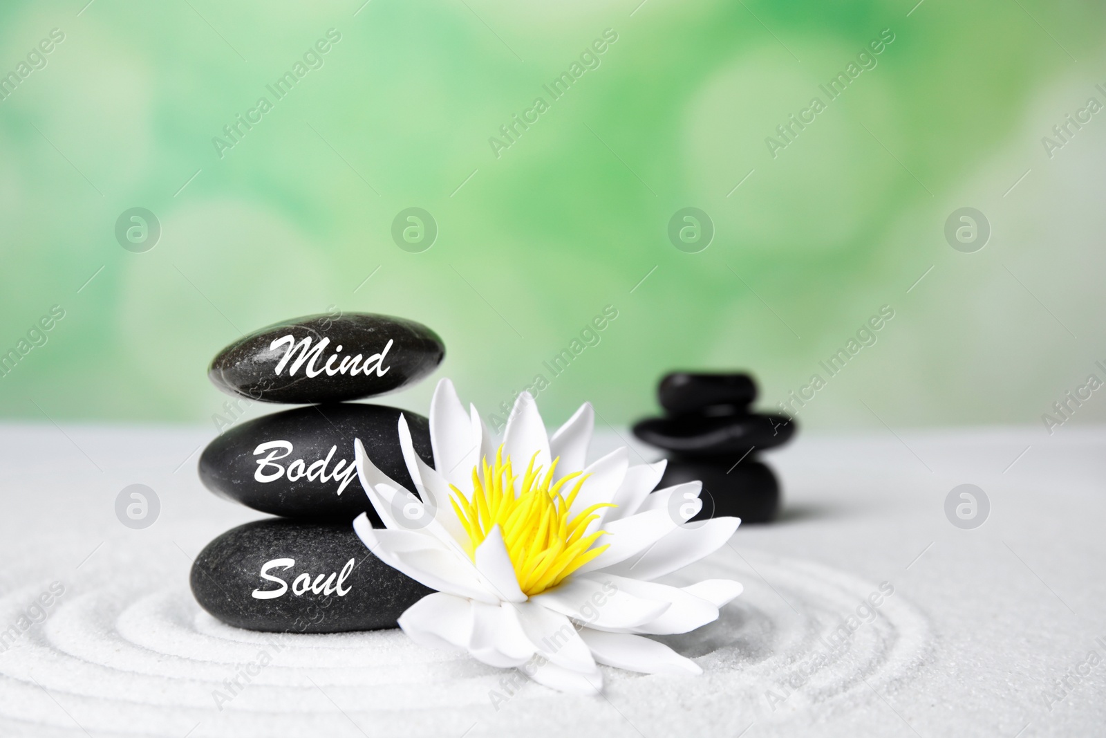 Photo of Stones with words Mind, Body, Soul and lotus flower on white sand. Zen garden