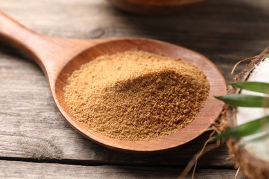 Photo of Spoon with coconut sugar on wooden table, closeup