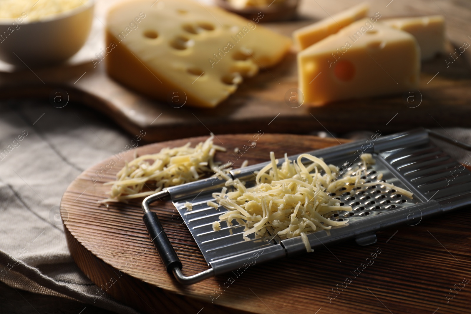 Photo of Grated, cut cheese and grater on table, closeup