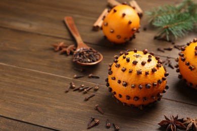 Pomander balls made of tangerines with cloves on wooden table. Space for text