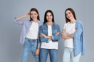 Photo of Group of young women in stylish jeans on grey background