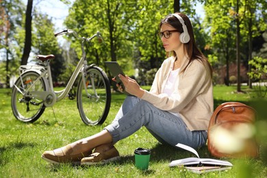 Woman with headphones and tablet working in park