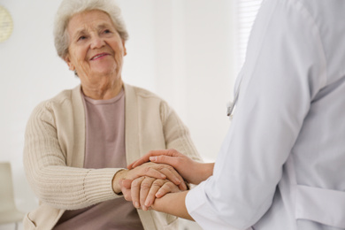 Doctor with senior patient in office, focus on hands