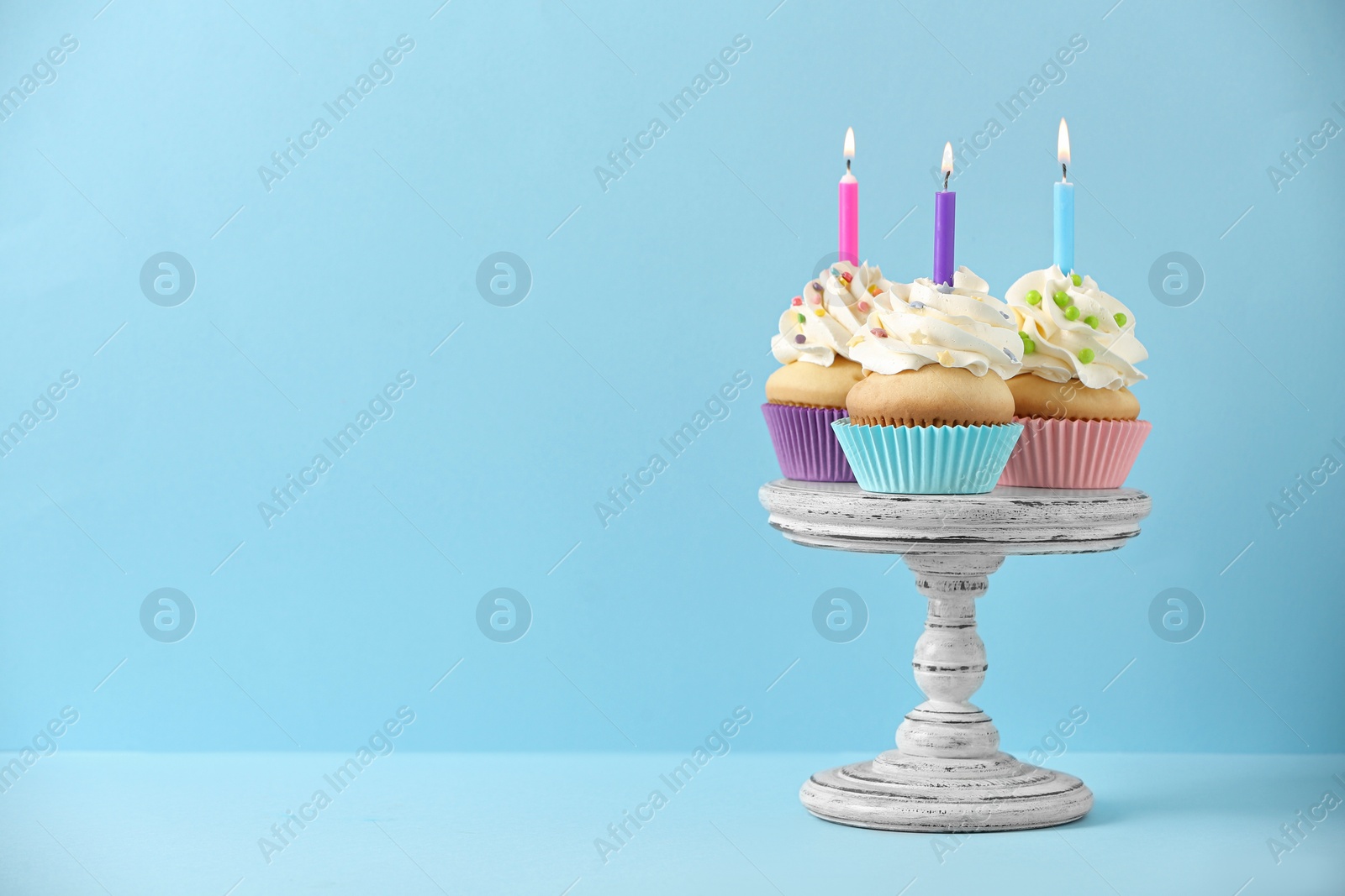 Photo of Birthday cupcakes with candles on light blue background, Space for text