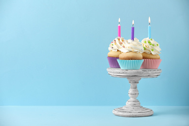 Birthday cupcakes with candles on light blue background, Space for text