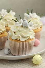 Tasty Easter cupcakes with vanilla cream and candies on table, closeup