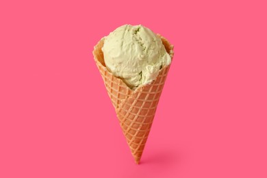 Photo of Delicious ice cream in waffle cone on pink background