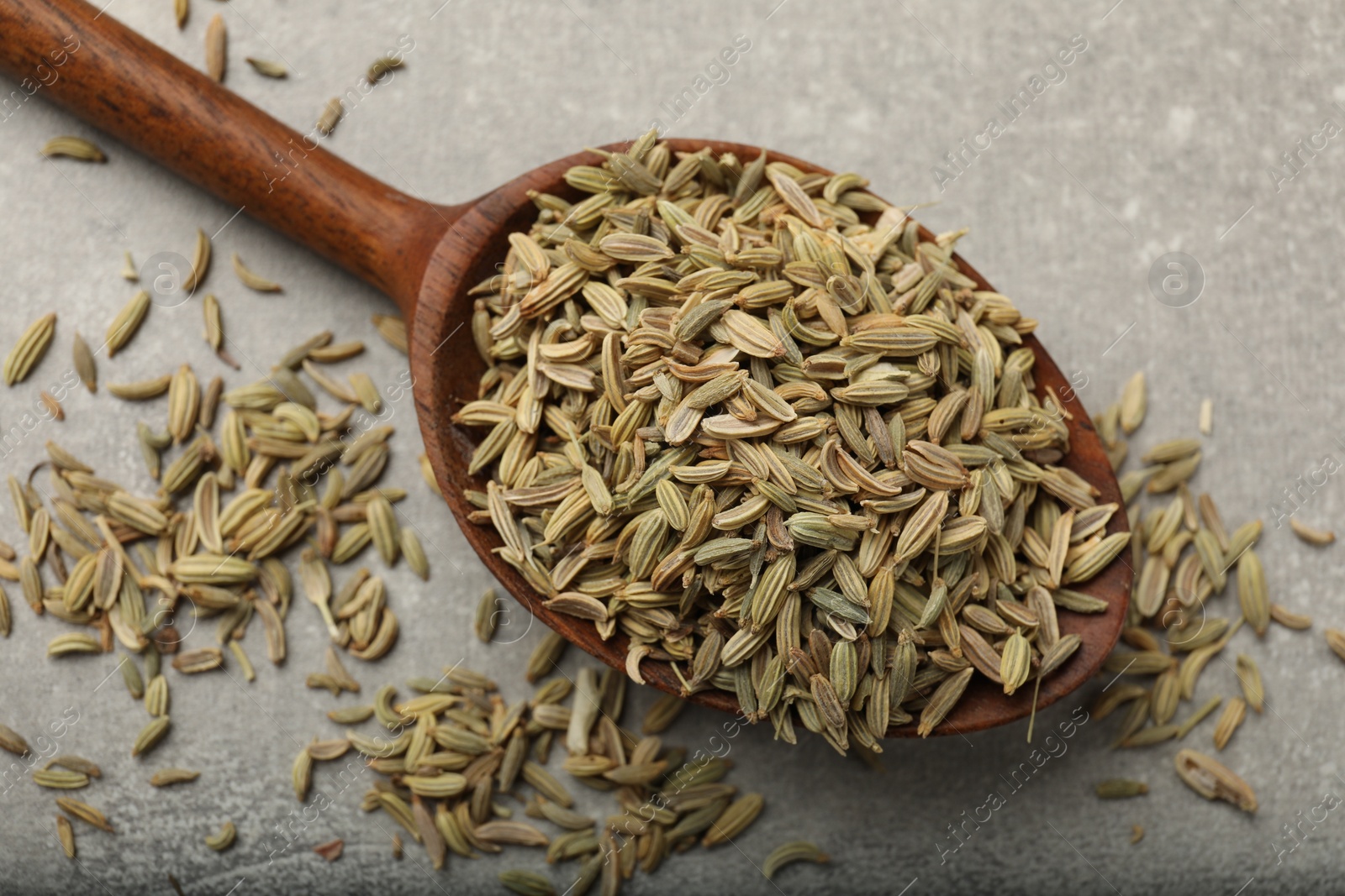 Photo of Wooden spoon with fennel seeds on grey table, top view