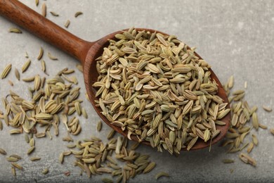 Wooden spoon with fennel seeds on grey table, top view