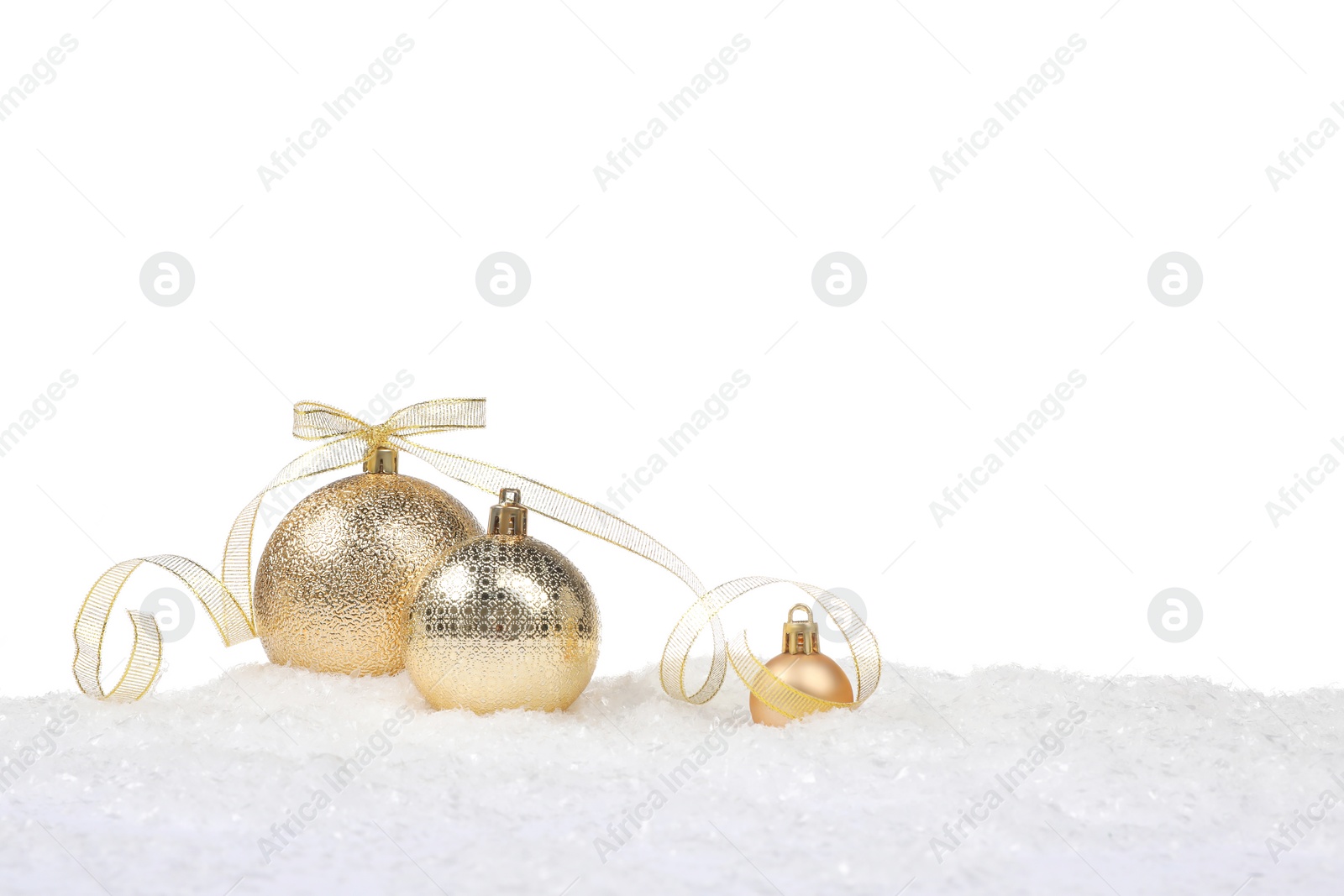 Photo of Beautiful golden Christmas balls with bow on snow against white background