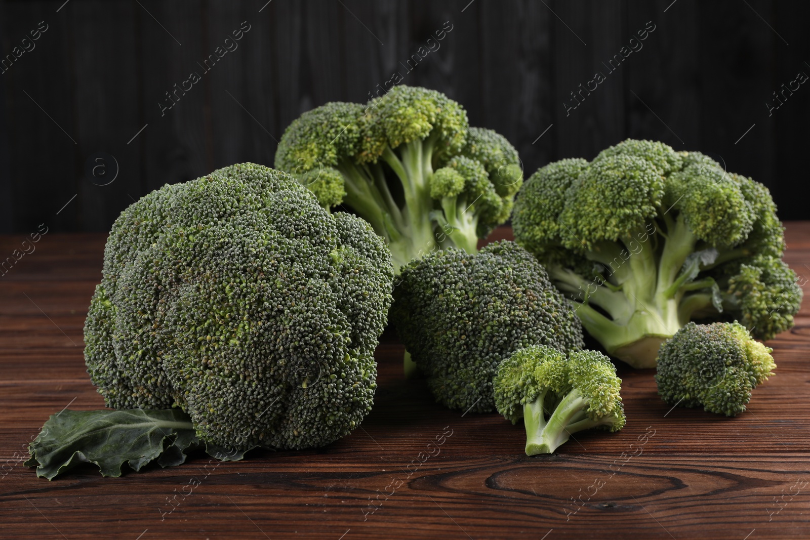 Photo of Fresh raw green broccoli on wooden table, closeup