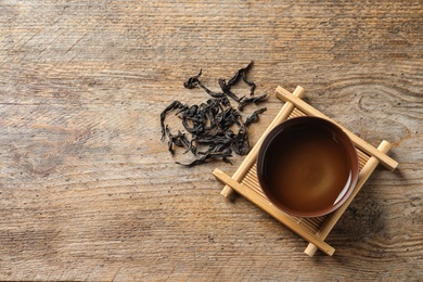 Photo of Cup of Da Hong Pao oolong and tea leaves on table, top view with space for text
