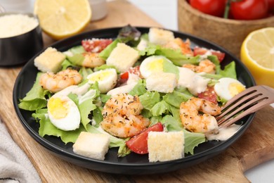 Delicious Caesar salad with shrimps and fork on table, closeup