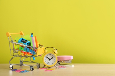 Photo of Set of school stationery and alarm clock on table against yellow background, space for text. Back to school