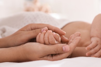 Photo of Mother with her cute baby on bed at home, closeup of hands