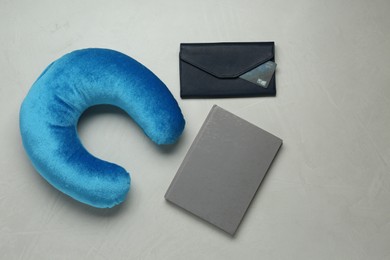 Photo of Light blue travel pillow, notebook and wallet with credit card on gray background, flat lay