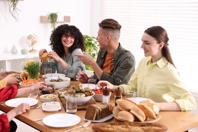 Photo of Friends eating vegetarian food at wooden table indoors