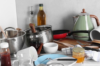 Photo of Many dirty utensils, cookware and dishware on countertop in messy kitchen