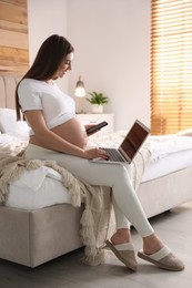 Photo of Pregnant woman working on bed at home. Maternity leave