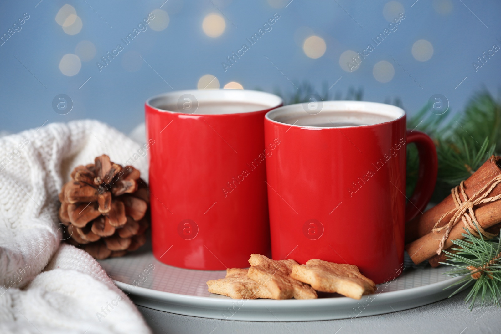 Photo of Composition with cups of tasty cocoa on table against blurred lights