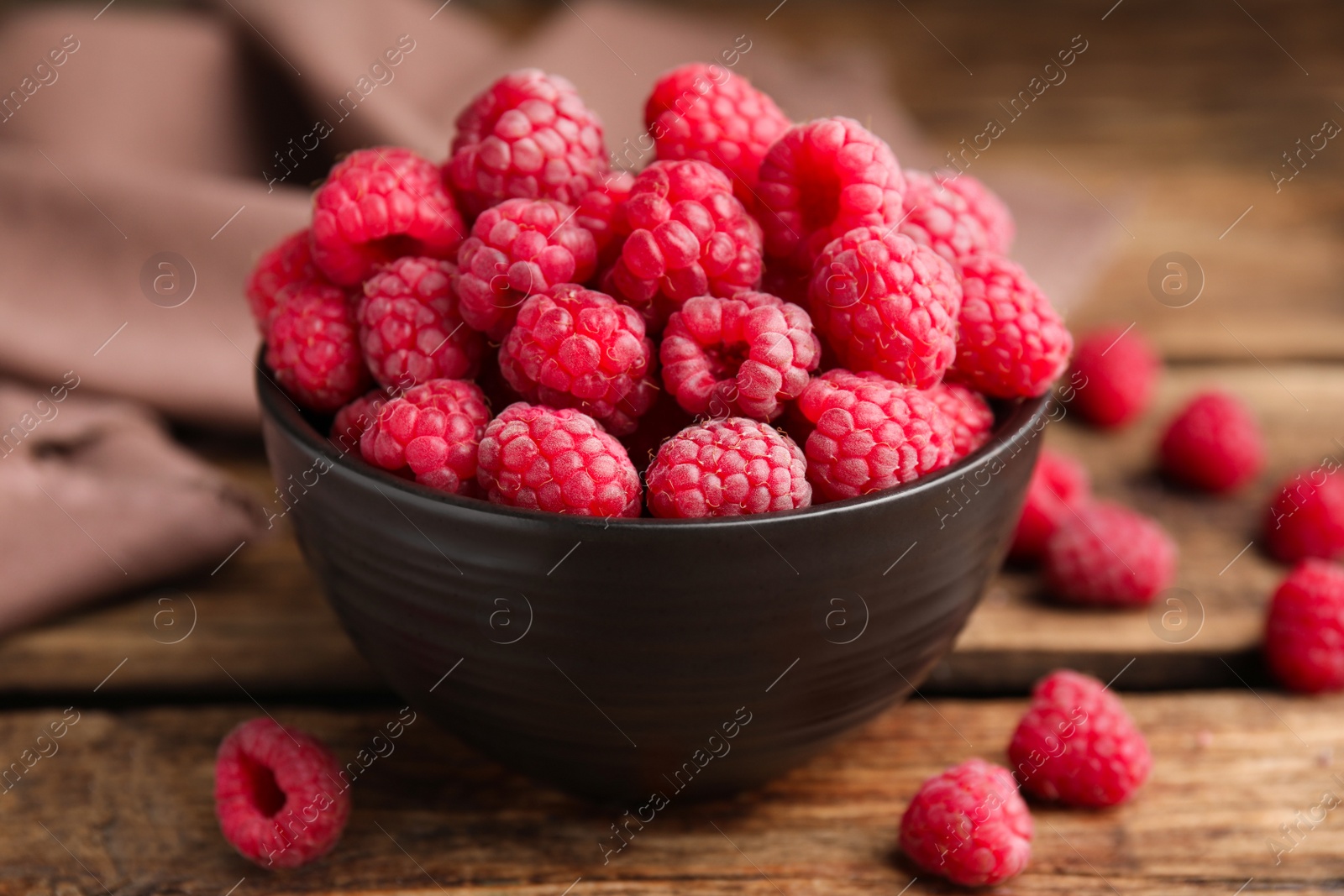 Photo of Bowl with fresh ripe raspberries on wooden table, closeup