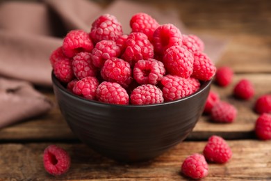Photo of Bowl with fresh ripe raspberries on wooden table, closeup