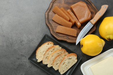 Photo of Delicious quince paste, bread, butter and fresh fruits on grey textured table, flat lay. Space for text